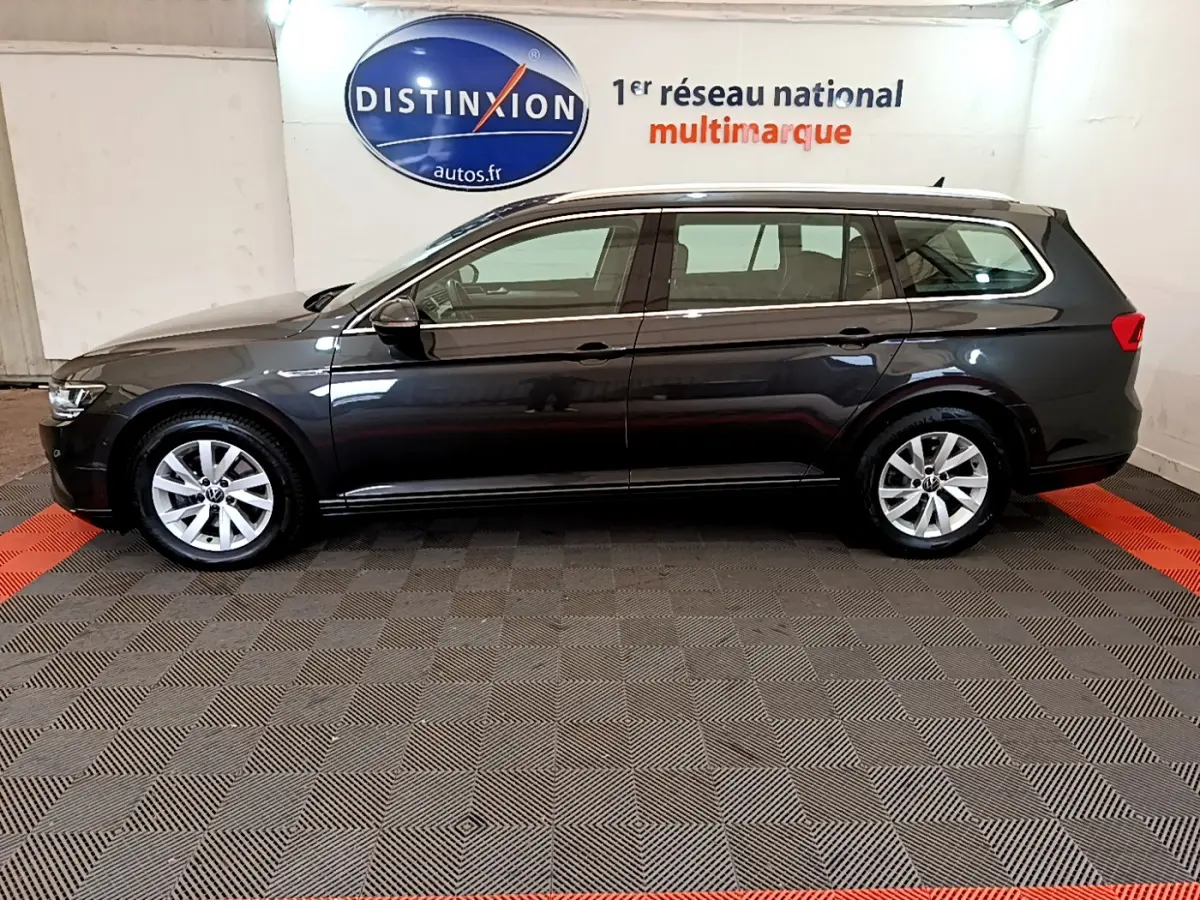 Profil côté gauche d'une Volkswagen Passat break gris foncé 2021, stationnée en intérieur sur sol damier.