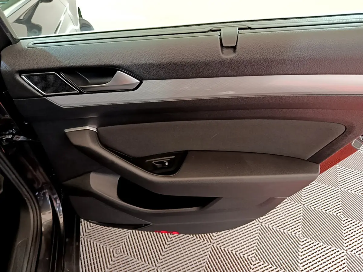 Gros plan sur la porte côté gauche gris foncé de la Volkswagen Passat 2021 avec poignée et commande de vitre intégrée.