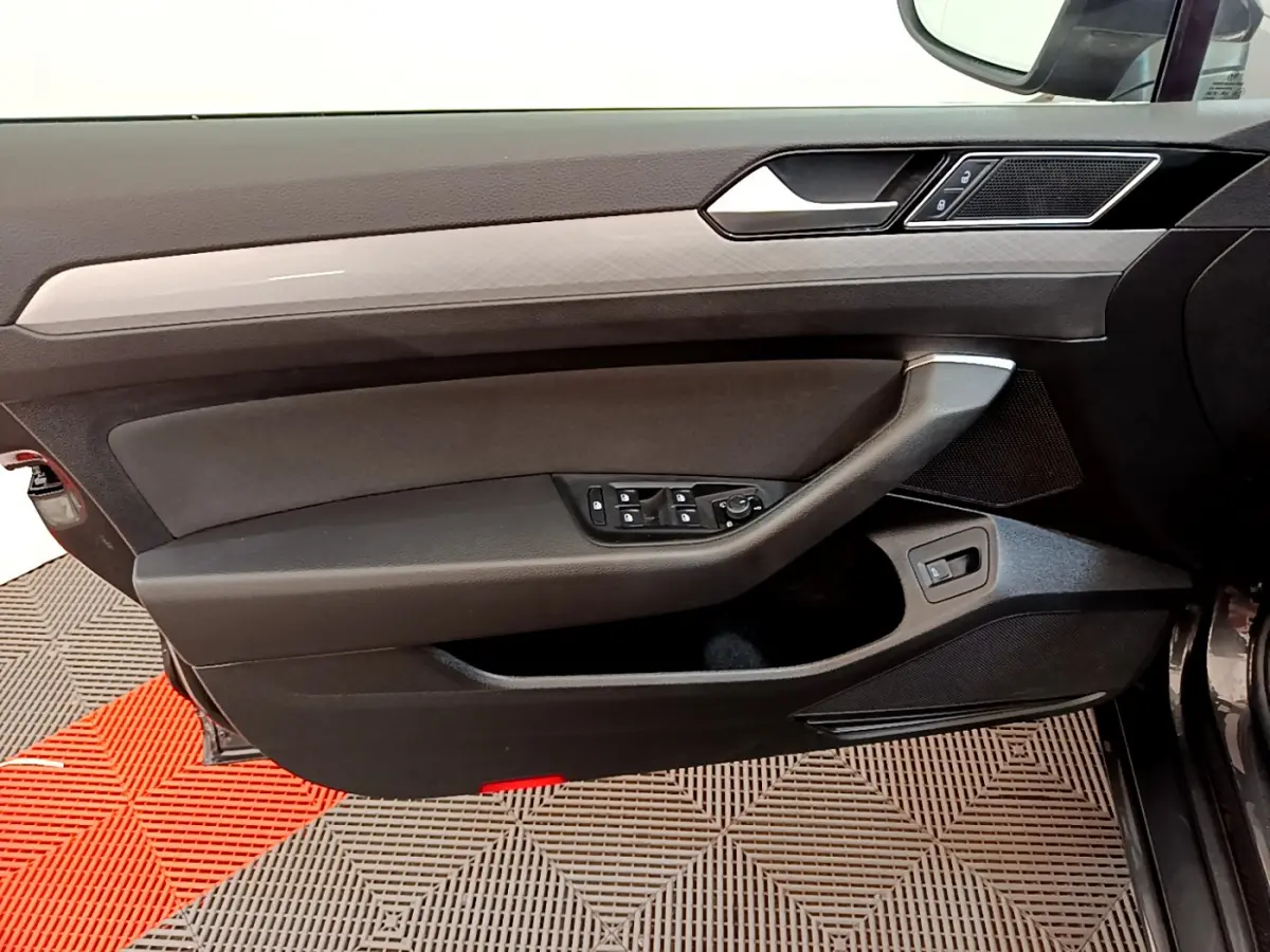Vue rapprochée de la porte avant gauche intérieure noire de la Volkswagen Passat 2.0 TDI 2021 avec commandes électriques.