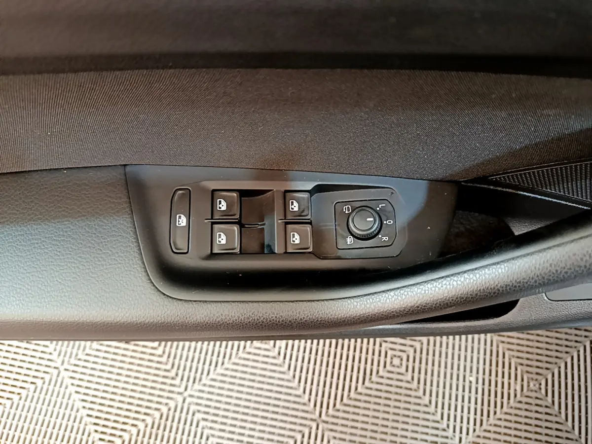 Commande des vitres et réglage des rétroviseurs côté conducteur sur la porte intérieure d'une Volkswagen Passat gris foncé.