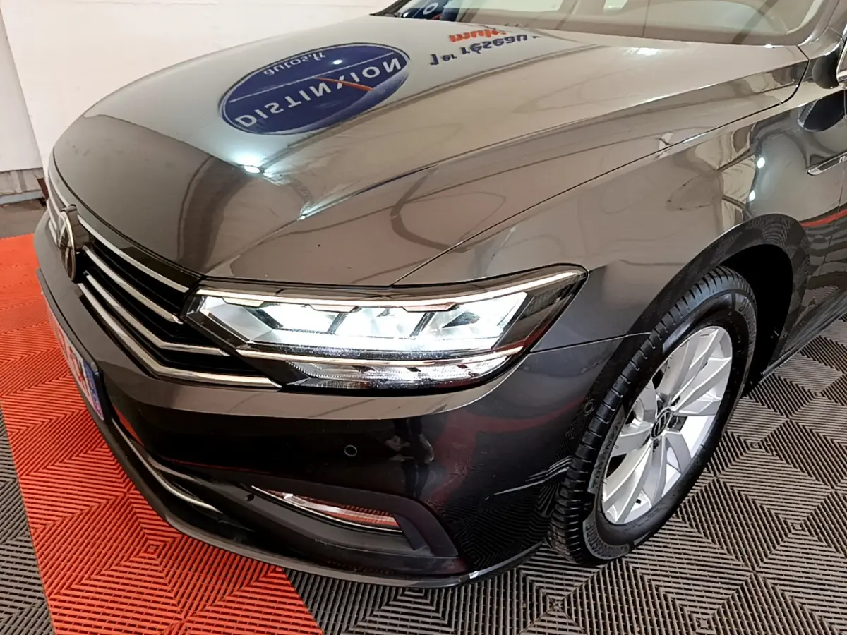 Vue 3/4 avant droit d'une Volkswagen Passat gris foncé avec phares LED allumés et jantes alliage visibles.