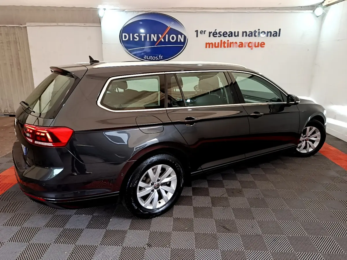 Volkswagen Passat break gris foncé vue 3/4 arrière droit en intérieur avec logo Distinxion en arrière-plan