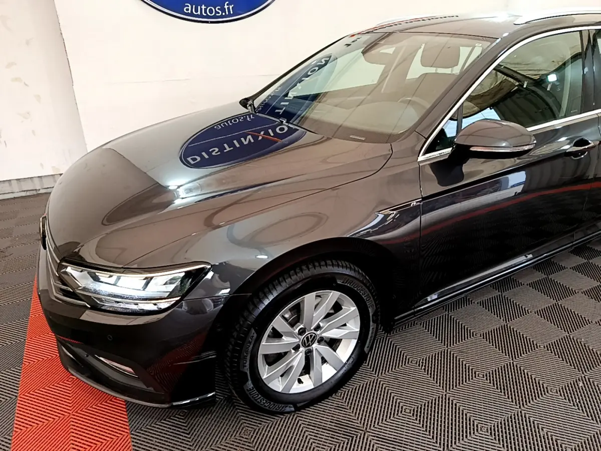 Volkswagen Passat gris foncé vue 3/4 avant droit, phares LED et jantes alliage visibles.