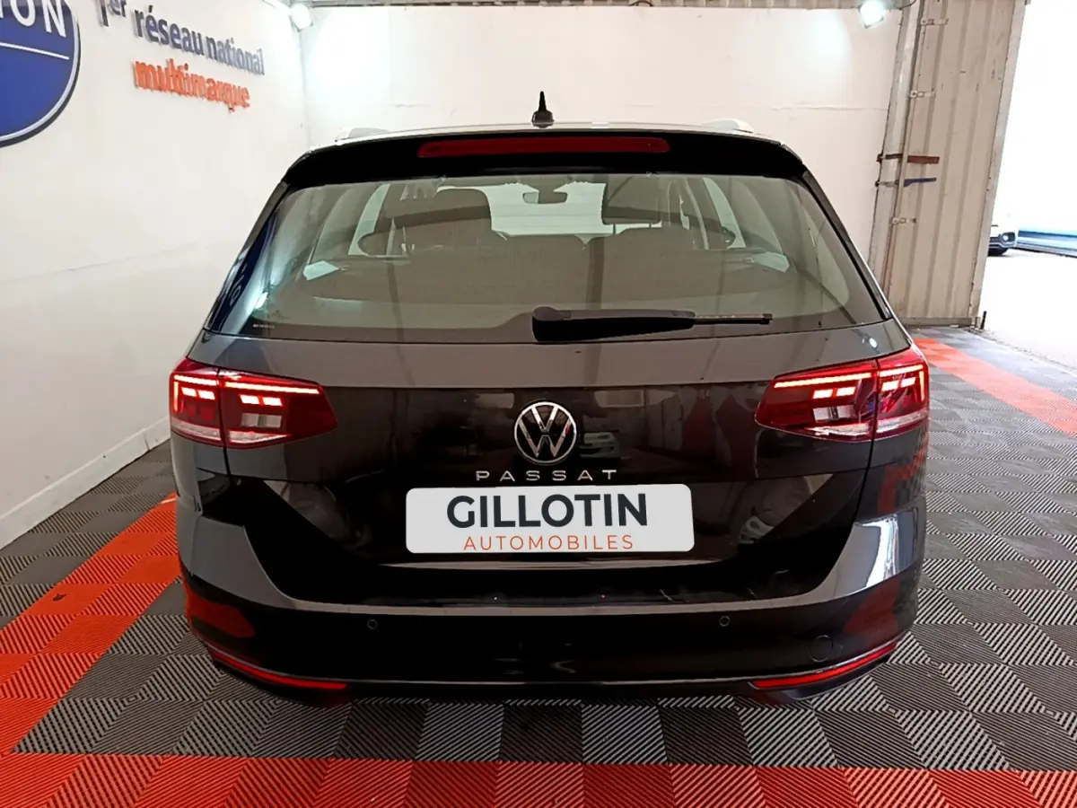 Vue arrière d'une Volkswagen Passat gris foncé avec feux LED allumés dans un garage.