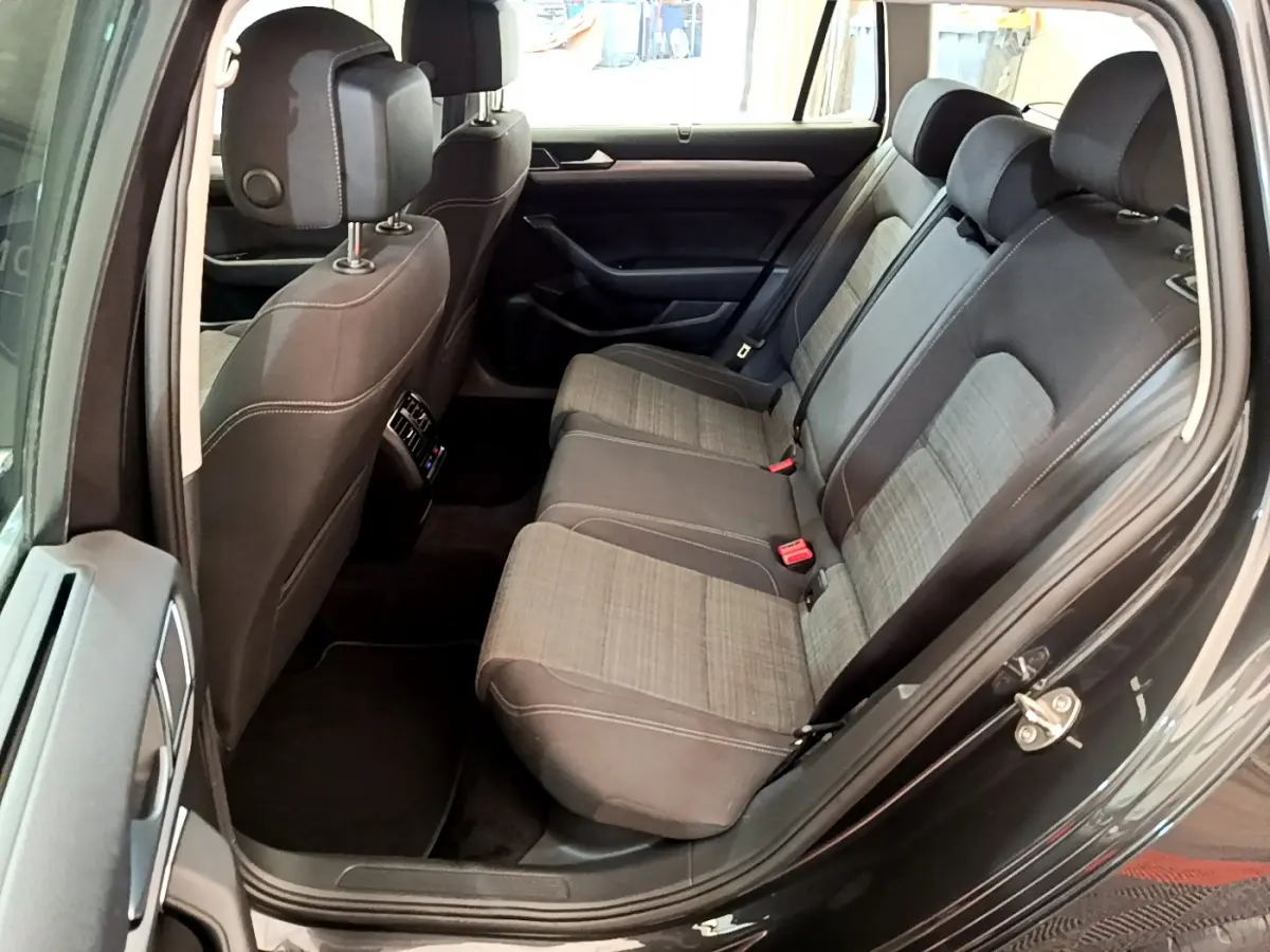 Vue côté gauche de l'habitacle arrière gris foncé de la Volkswagen Passat 2021 avec sièges tissu bicolore et appuie-têtes.