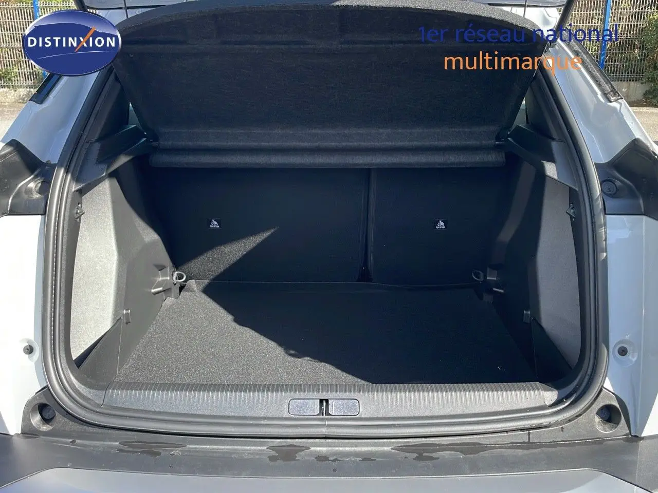 Coffre ouvert d'un Peugeot 2008 blanc Okenite Metal, montrant l'espace de chargement intérieur vide.