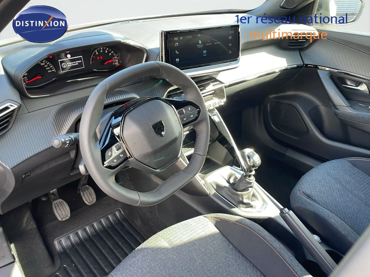 Intérieur du Peugeot 2008 2025 en tissu gris, vue côté conducteur montrant volant, tableau de bord et levier de vitesses manuel.