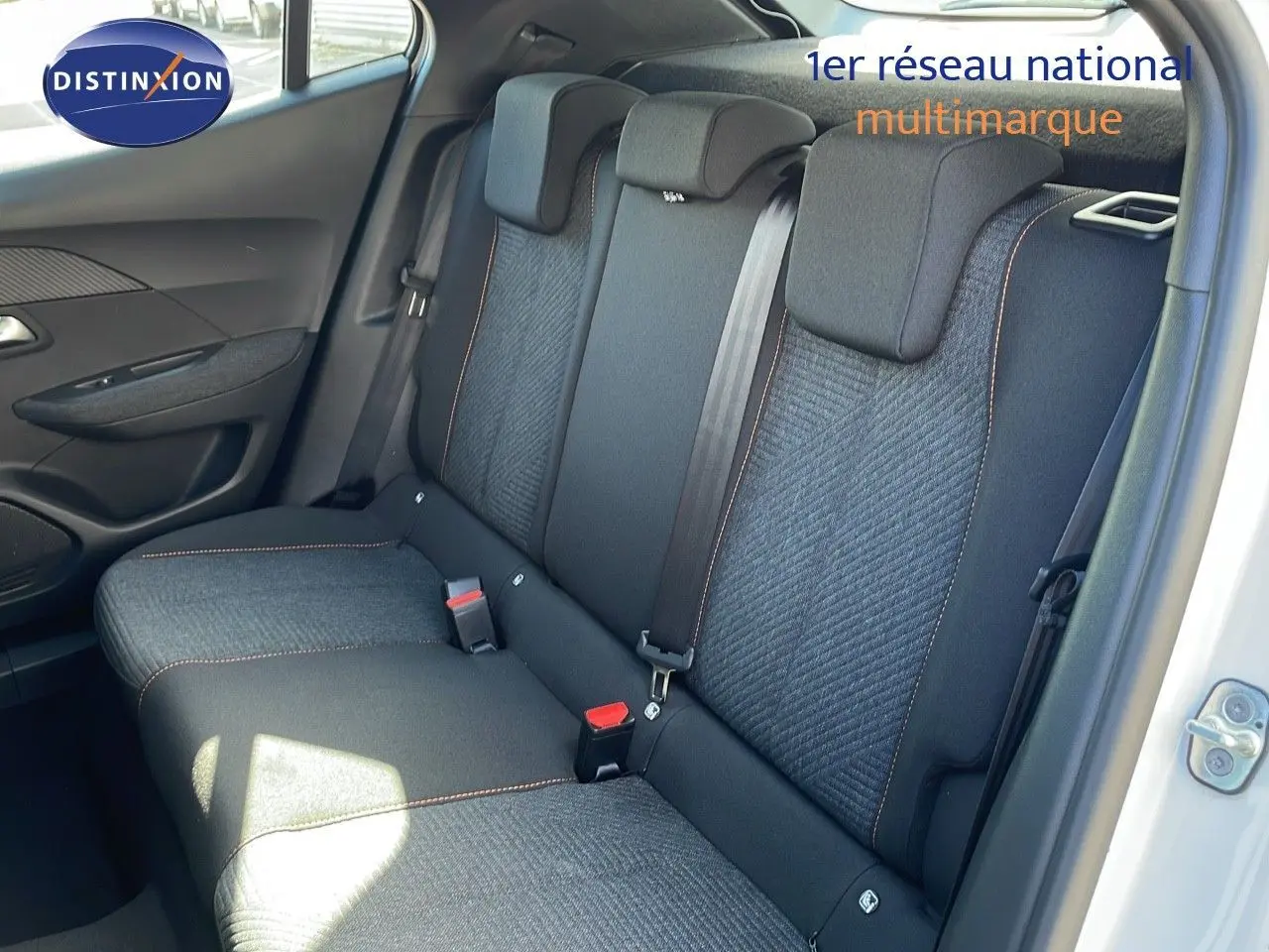 Vue intérieure du siège arrière côté droit d'un Peugeot 2008 blanc Okenite Metal avec sellerie tissu gris et surpiqûres orange.
