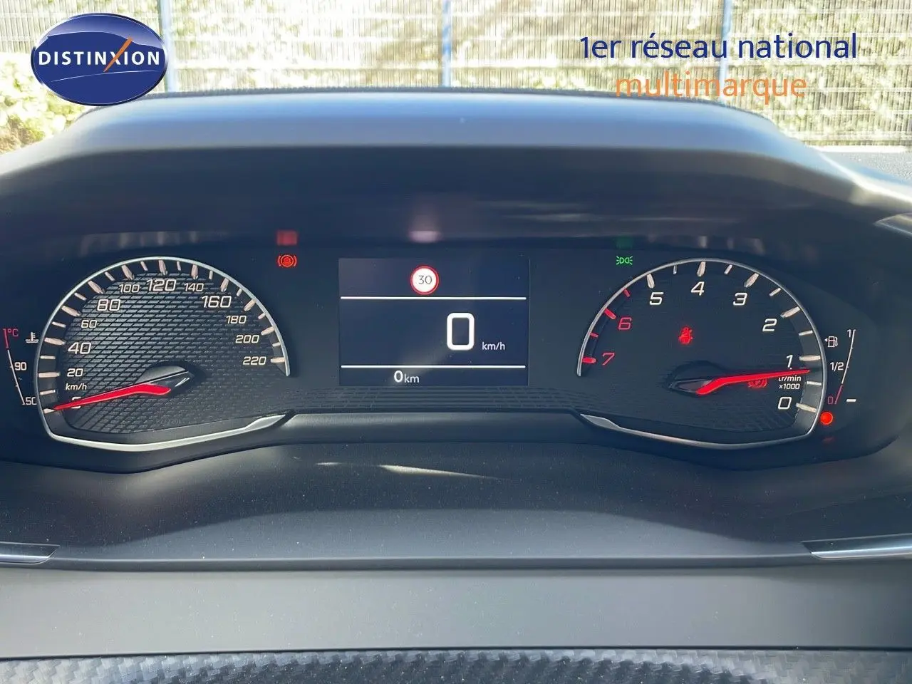 Tableau de bord numérique du Peugeot 2008 blanc, affichant vitesse à 0 km/h et compte-tours au ralenti.