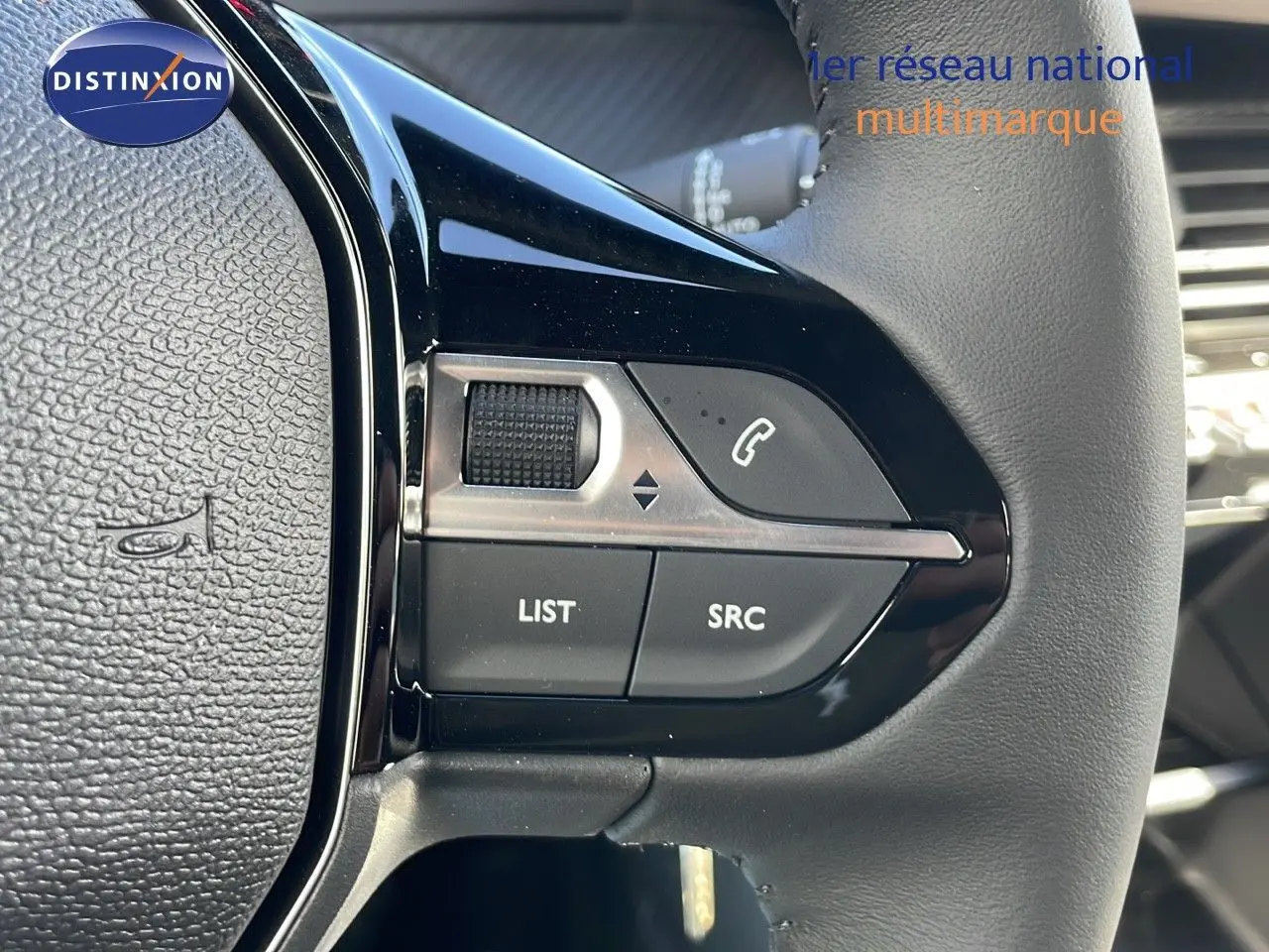 Gros plan sur les commandes gauche du volant du Peugeot 2008 blanc Okenite Metal, avec boutons audio et téléphone intégrés.