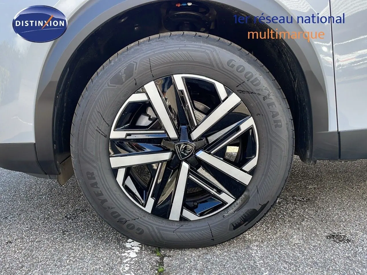 Gros plan sur la roue avant gauche d'un Peugeot 2008 blanc Okenite avec jante alliage bicolore moderne.