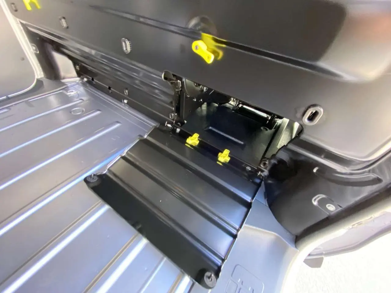 Détail du plancher intérieur gris métallisé du Peugeot Expert Fourgon 1.5 BlueHDi 120 Premium avec trappe et fixations jaunes.
