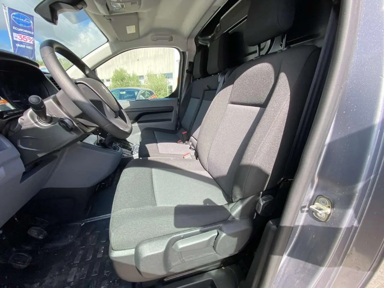 Vue intérieure côté conducteur du Peugeot Expert Fourgon gris Artense, montrant la banquette passager 2 places Moduwork et le volant réglable.