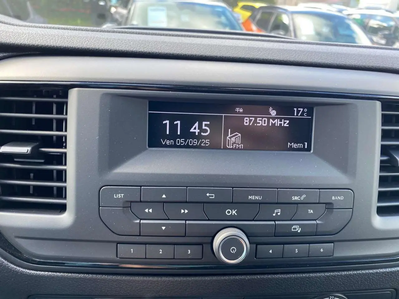 Tableau de bord du Peugeot Expert Fourgon gris Artense, affichant l'horloge et la radio FM à 87,5 MHz.