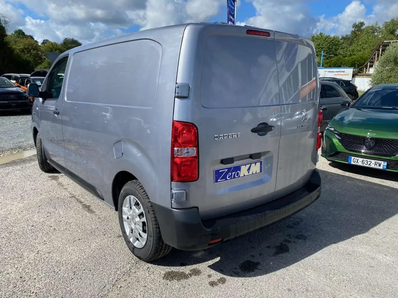 Vue 3/4 arrière droite du Peugeot Expert Fourgon gris Artense métallisé avec portes battantes et roue de secours visible.