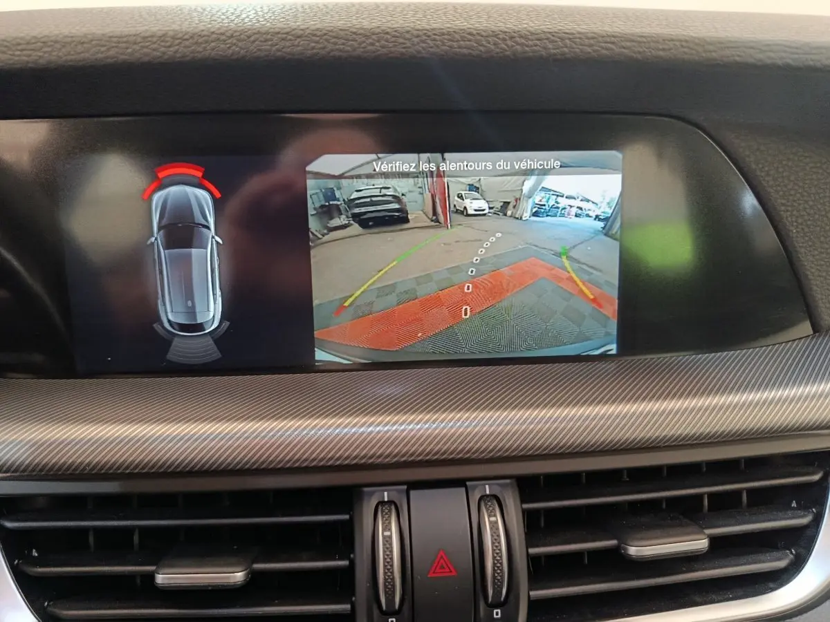 Écran tactile central affichant la caméra de recul et les capteurs de stationnement de l'Alfa Romeo Stelvio gris foncé.