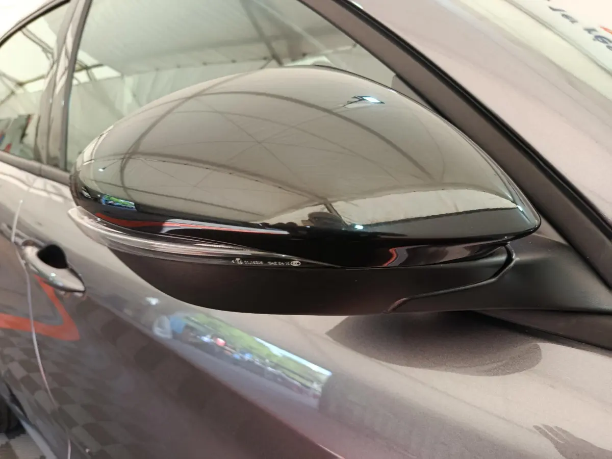 Rétroviseur droit noir brillant sur Alfa Romeo Stelvio gris foncé, vue rapprochée du côté passager.