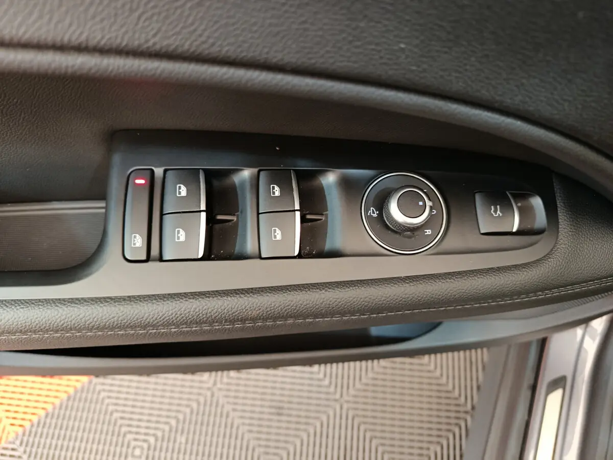 Gros plan sur les commandes de lève-vitres et rétroviseurs côté conducteur d'un Alfa Romeo Stelvio gris foncé 2024.