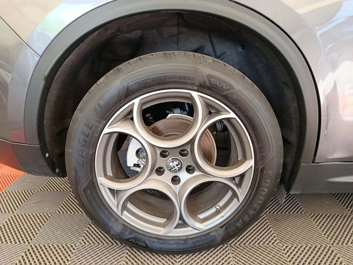 Gros plan sur la roue avant droite gris foncé d'un Alfa Romeo Stelvio 2.2 TD 160 AT8 Sprint avec jante distinctive à cinq cercles.