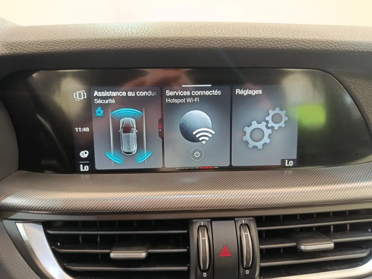 Écran tactile central affichant l'assistance à la conduite, services connectés et réglages dans l'Alfa Romeo Stelvio 2024.