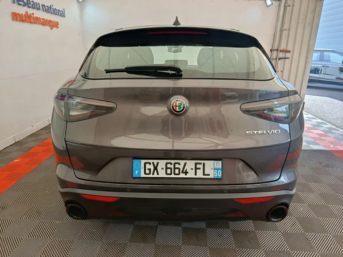 Vue arrière d'un Alfa Romeo Stelvio gris foncé 2024 avec feux LED et double sortie d'échappement ronde.