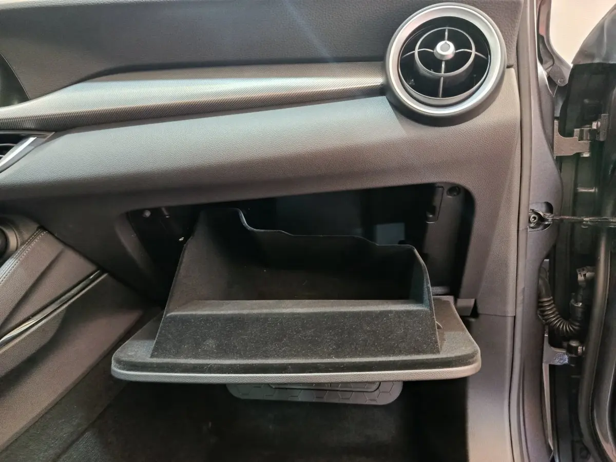 Gant de rangement ouvert côté passager de l'Alfa Romeo Stelvio gris foncé, montrant la texture intérieure noire.