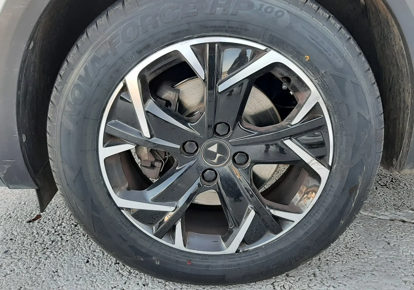 Gros plan sur la roue avant droite du DS3 Crossback blanc perle, jante alliage noir et argent avec logo DS central.