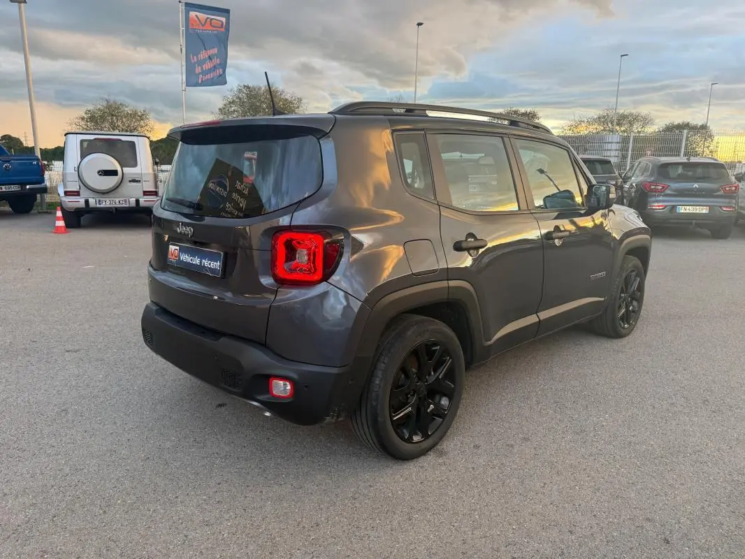 Jeep Renegade gris anthracite vue 3/4 arrière droit, avec barres de toit et jantes alliage noires 18 pouces.