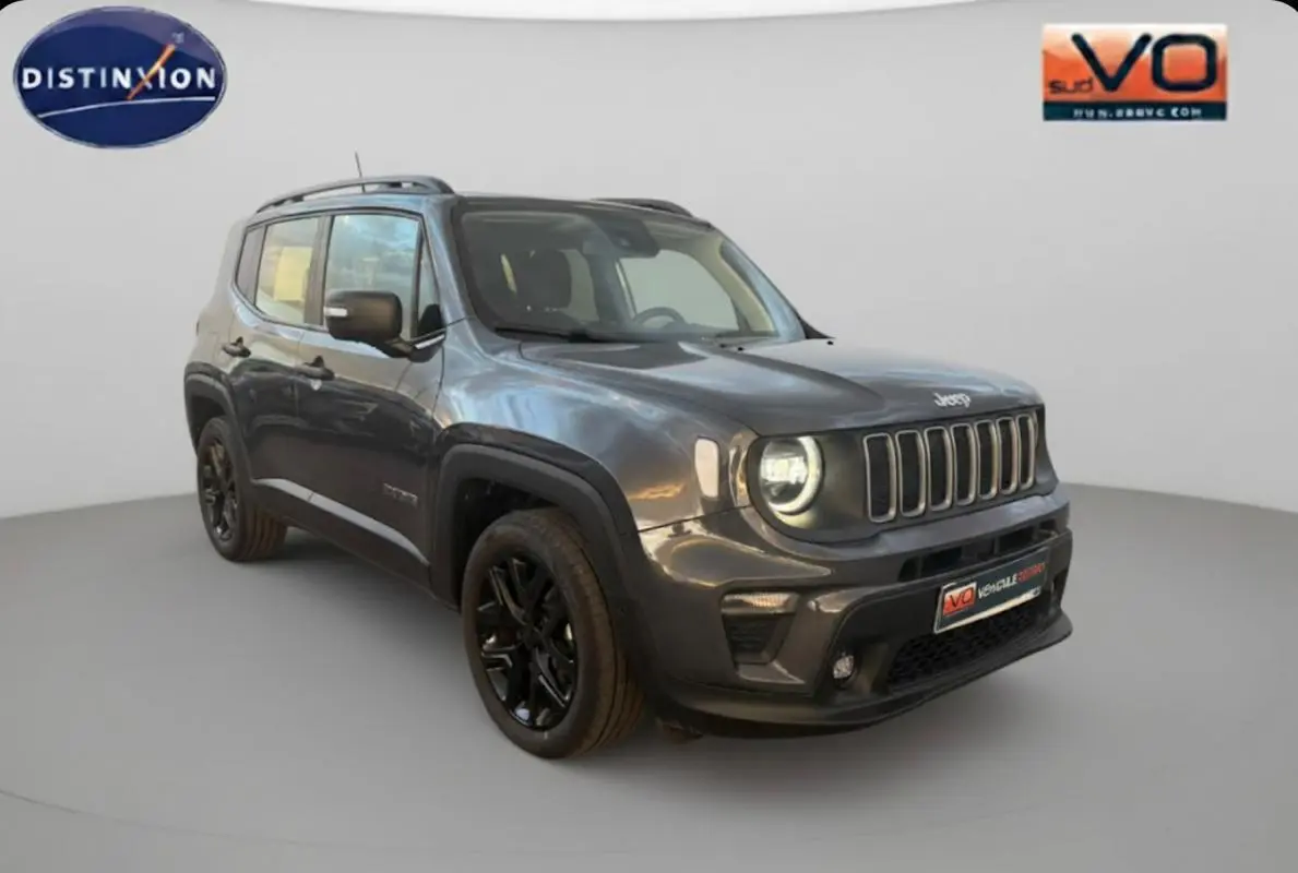 Jeep Renegade gris anthracite en 3/4 avant droit avec jantes alliage noires et barres de toit visibles.