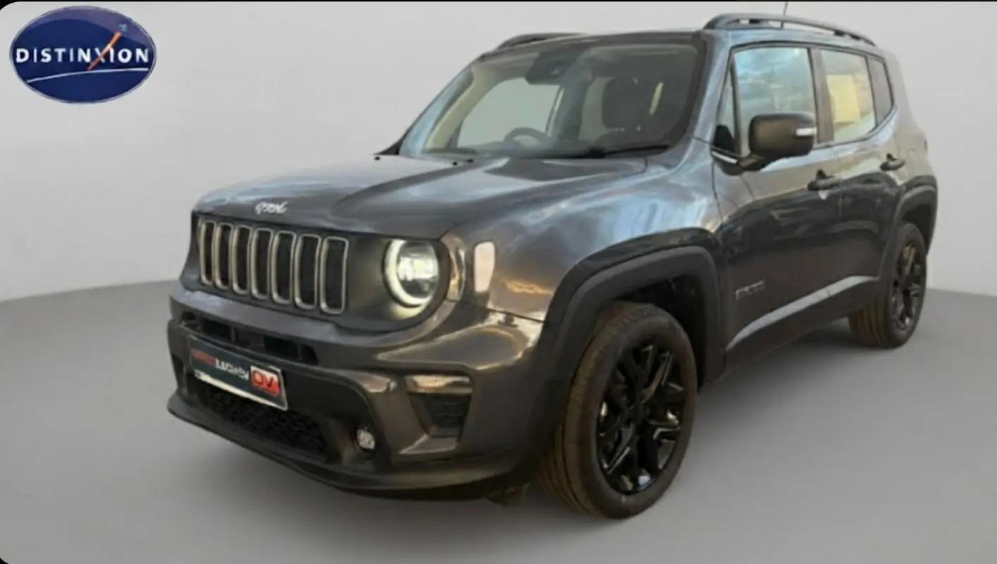 Jeep Renegade gris anthracite en 3/4 avant droit, avec jantes alliage noires et barres de toit visibles.