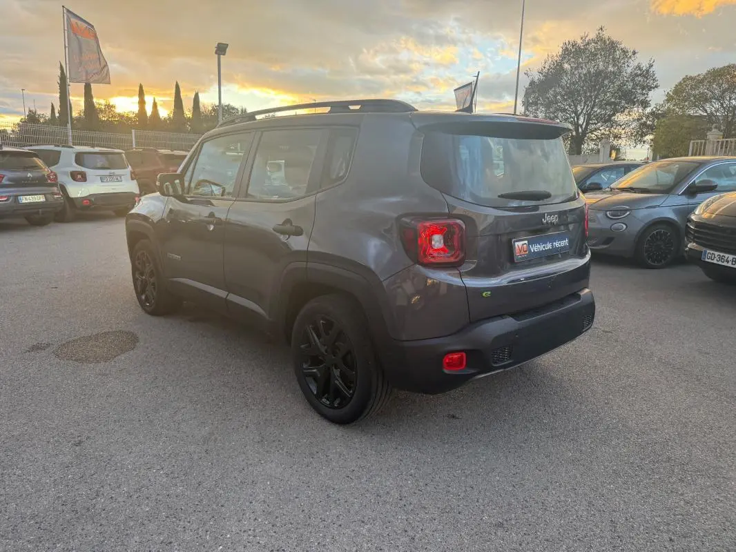 Jeep Renegade gris anthracite vue 3/4 arrière droit, avec barres de toit et jantes alliage noires de 18 pouces.