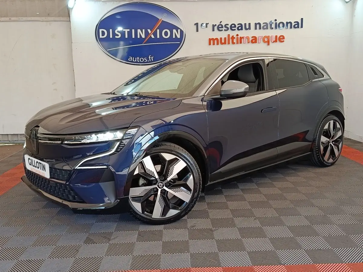 Vue 3/4 avant droite d'une Renault Mégane Techno EV60 bleu électrique avec jantes distinctives et phares LED allumés.