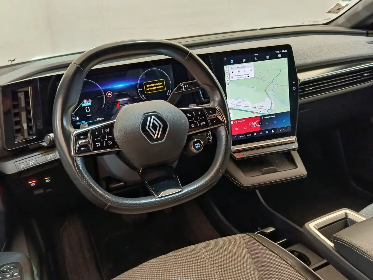 Intérieur Renault Mégane Techno EV60 2023, vue tableau de bord avec volant cuir et grand écran tactile vertical.