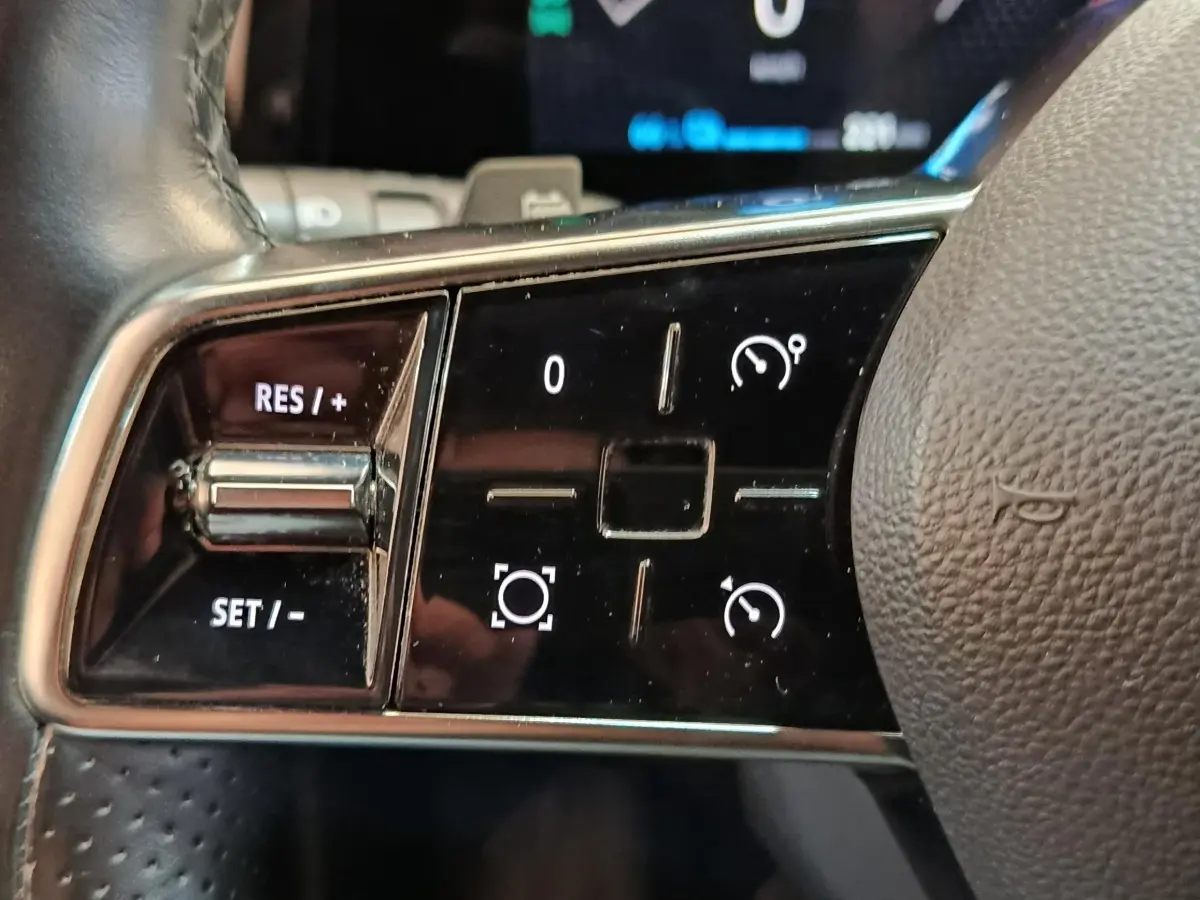 Gros plan sur les commandes du volant cuir noir de la Renault Mégane Techno EV60 2023, boutons de régulateur de vitesse.