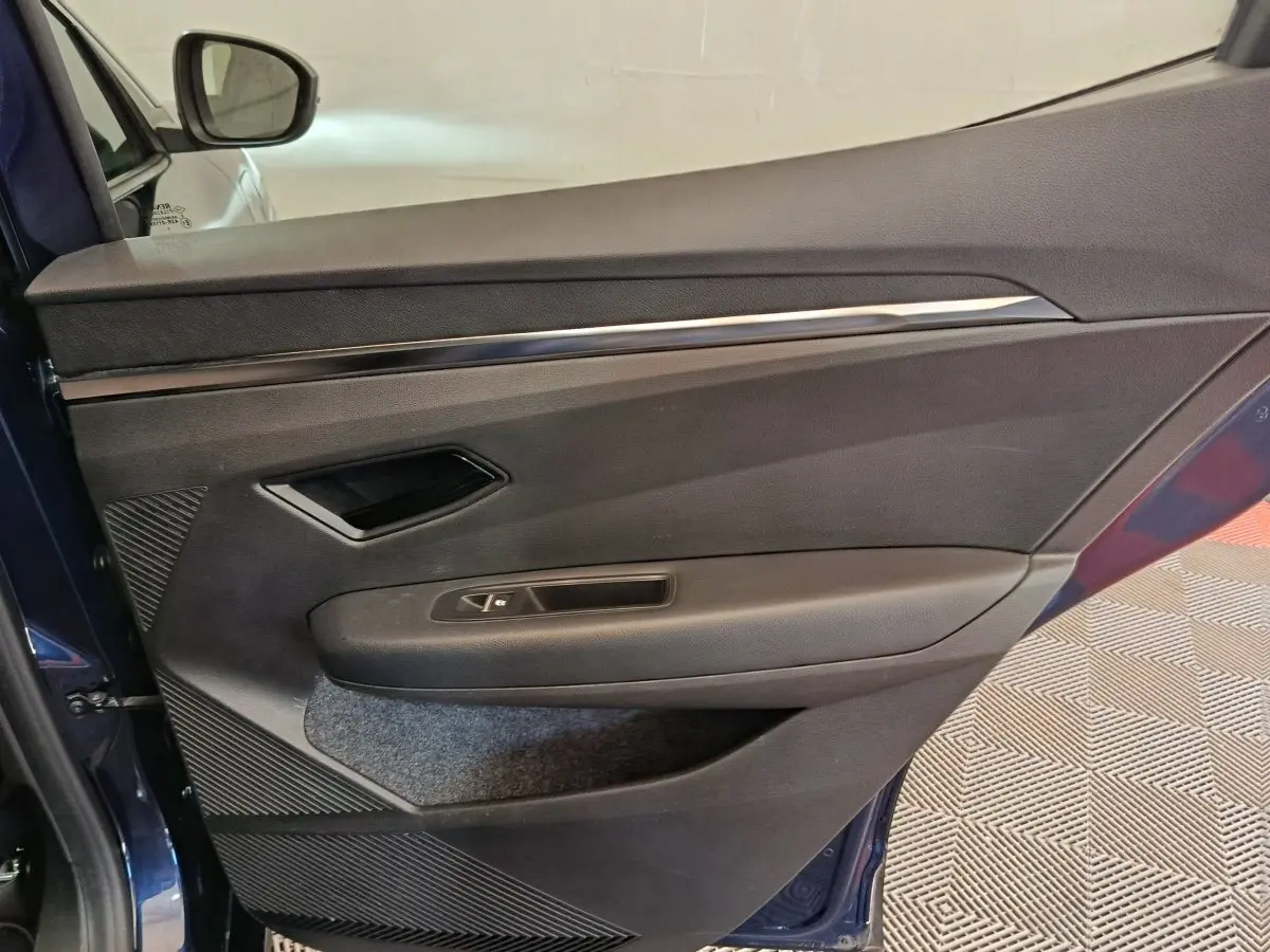 Intérieur de la porte côté gauche de la Renault Megane Techno EV60 bleu, avec poignée et commande de fenêtre.