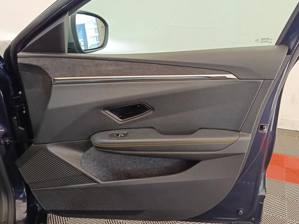 Vue intérieure de la porte avant gauche bleu foncé de la Renault Mégane 2023 avec surpiqûres jaunes et insert tissu.