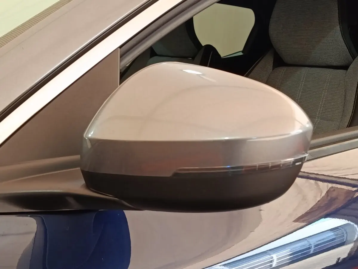 Rétroviseur côté conducteur gris sur Renault Mégane Techno EV60 bleu, vue rapprochée avec siège arrière visible.