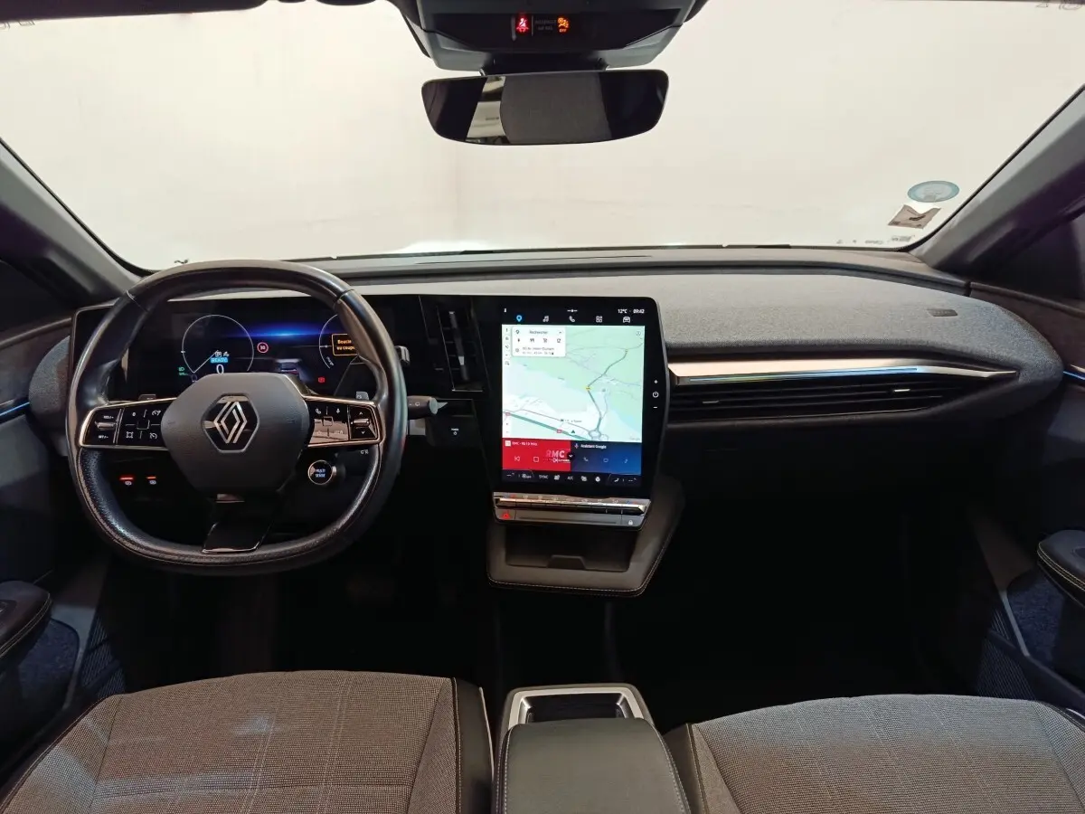 Vue intérieure avant de la Renault Mégane Techno EV60 220ch avec tableau de bord moderne et écran tactile vertical.