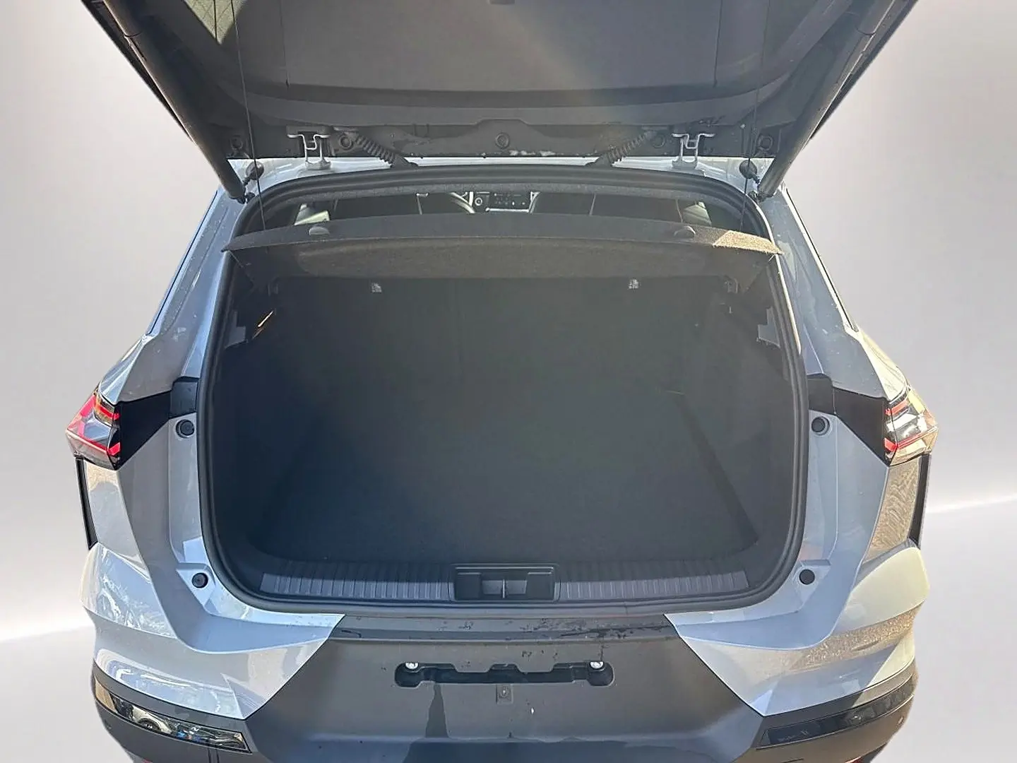Vue arrière du coffre ouvert du Renault Symbioz gris rafale, mettant en valeur son espace de rangement.