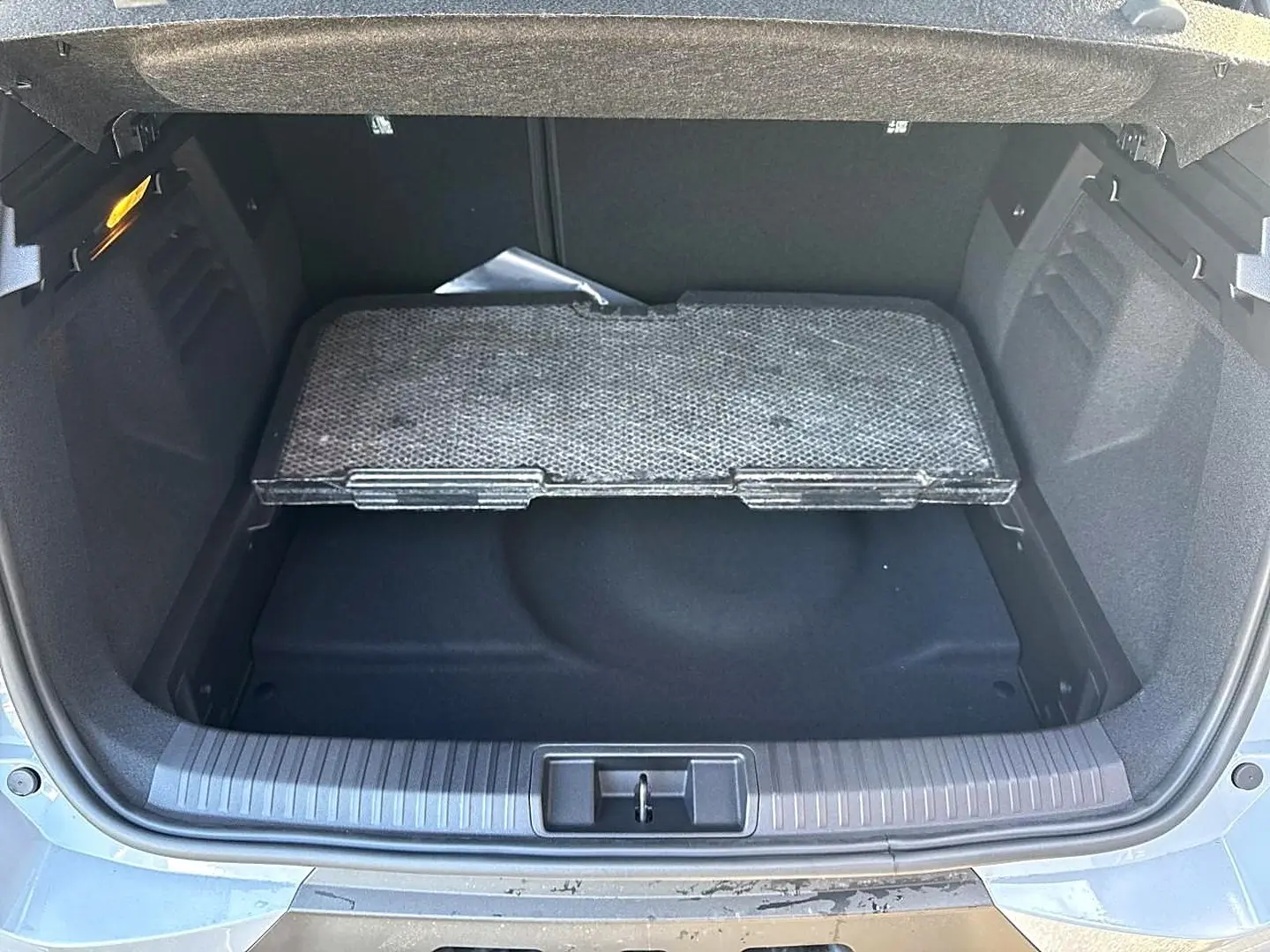 Vue plongeante sur le coffre ouvert gris rafale du Renault Symbioz 2026 avec plancher de coffre mobile visible.