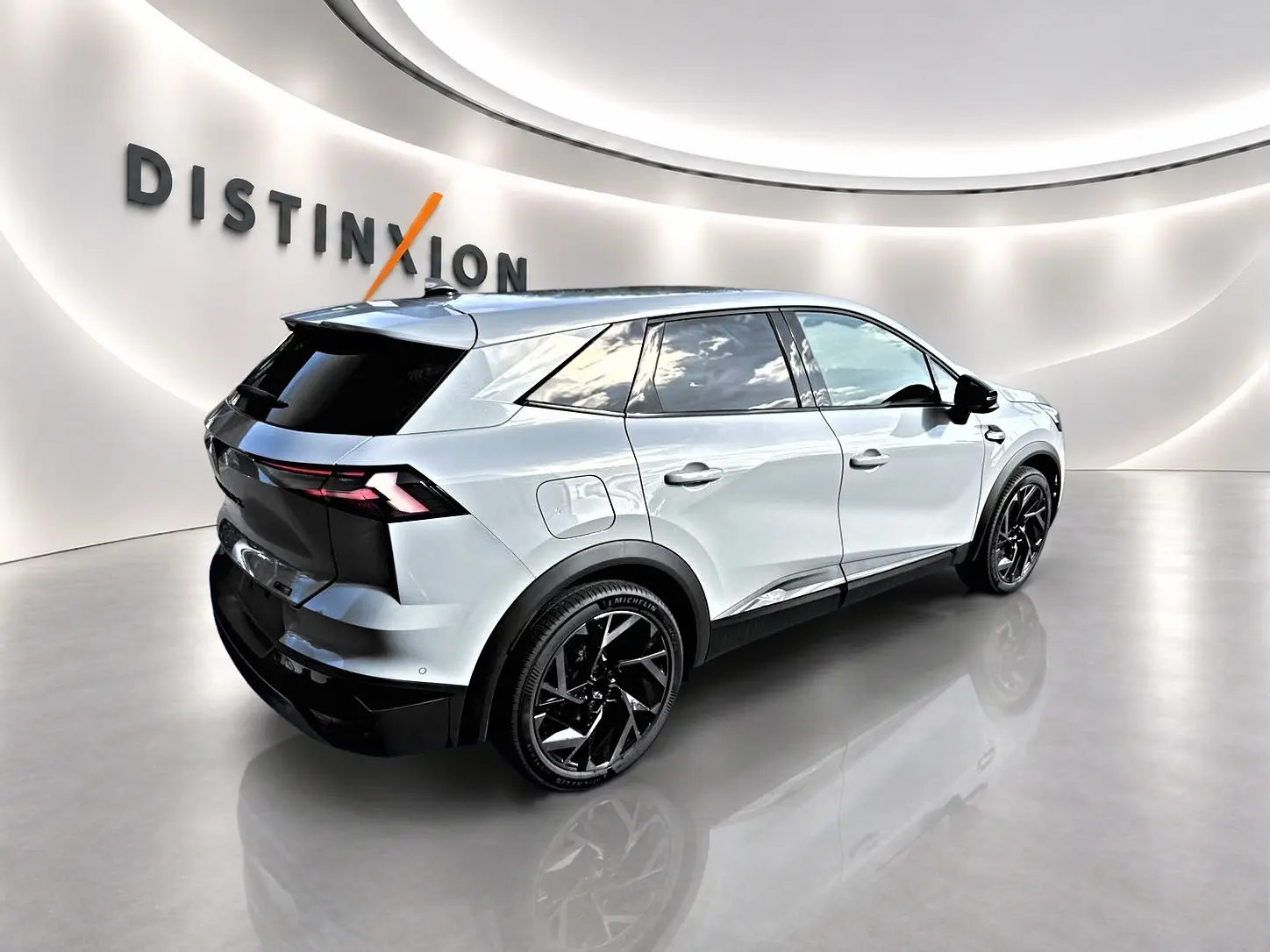 Vue 3/4 arrière droite du Renault Symbioz gris rafale avec jantes noires et vitres teintées dans un showroom lumineux.