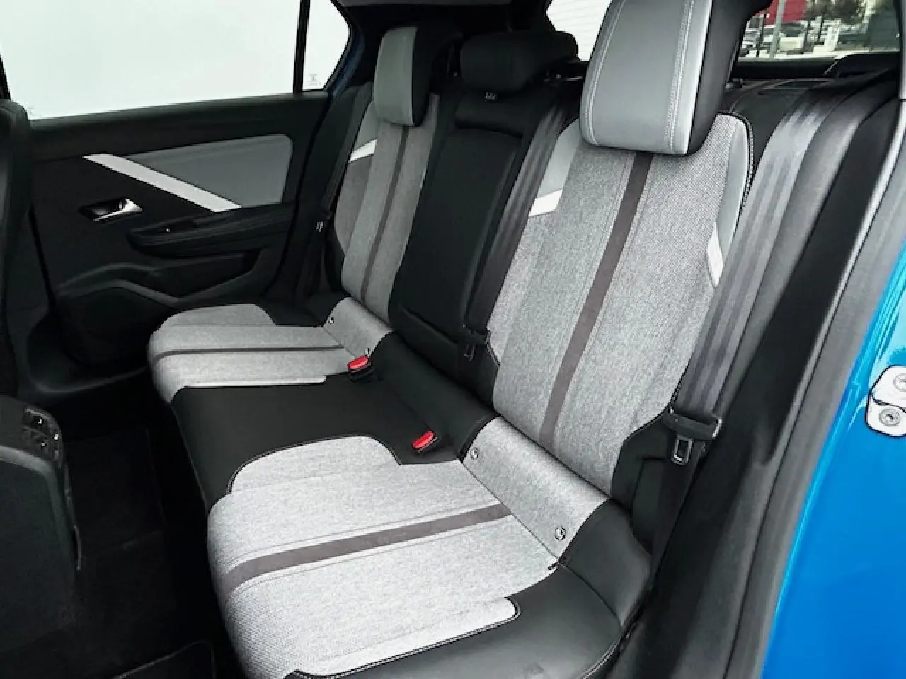 Vue latérale droite de la banquette arrière grise et noire de l'Opel Astra VI bleu clair, avec ceinture et appuis-tête visibles.
