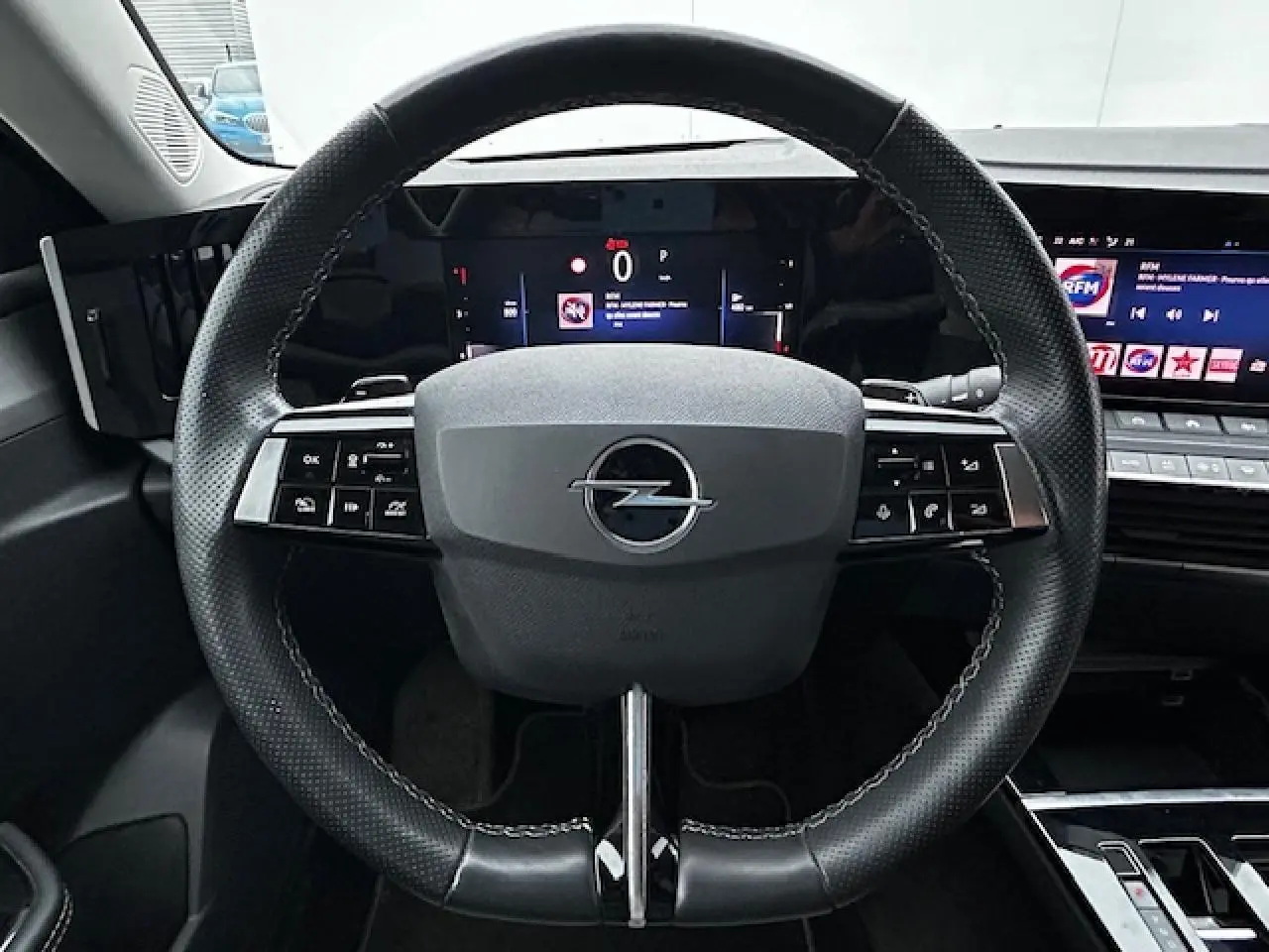 Volant cuir noir de l'Opel Astra VI diesel 2022 vu de face avec tableau de bord numérique et écran multimédia.