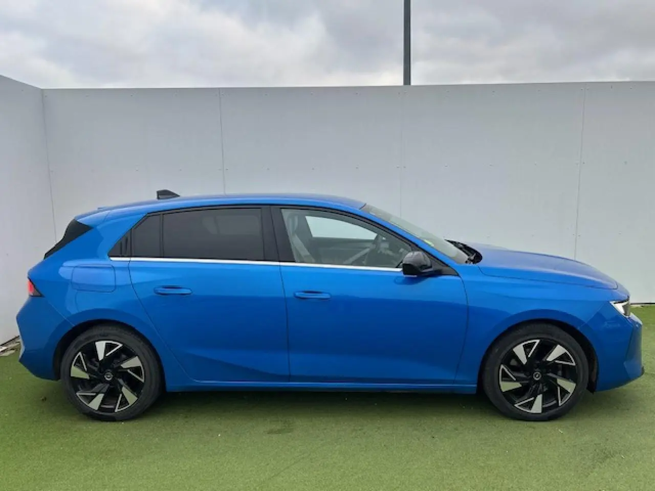 Opel Astra VI bleu clair vue de profil côté gauche avec jantes alliage noires et vitres surteintées.