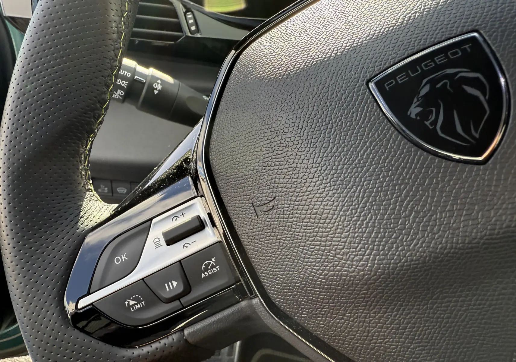 Gros plan sur le volant en cuir noir perforé avec logo Peugeot du 308 SW BlueHDi 130 EAT8 GT 2024.