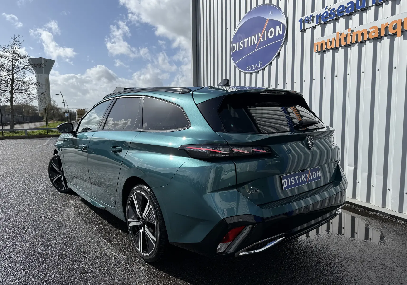 Peugeot 308 SW Bleu Avatar vue 3/4 arrière droit, avec jantes alliage et vitres teintées, stationnée devant un bâtiment.