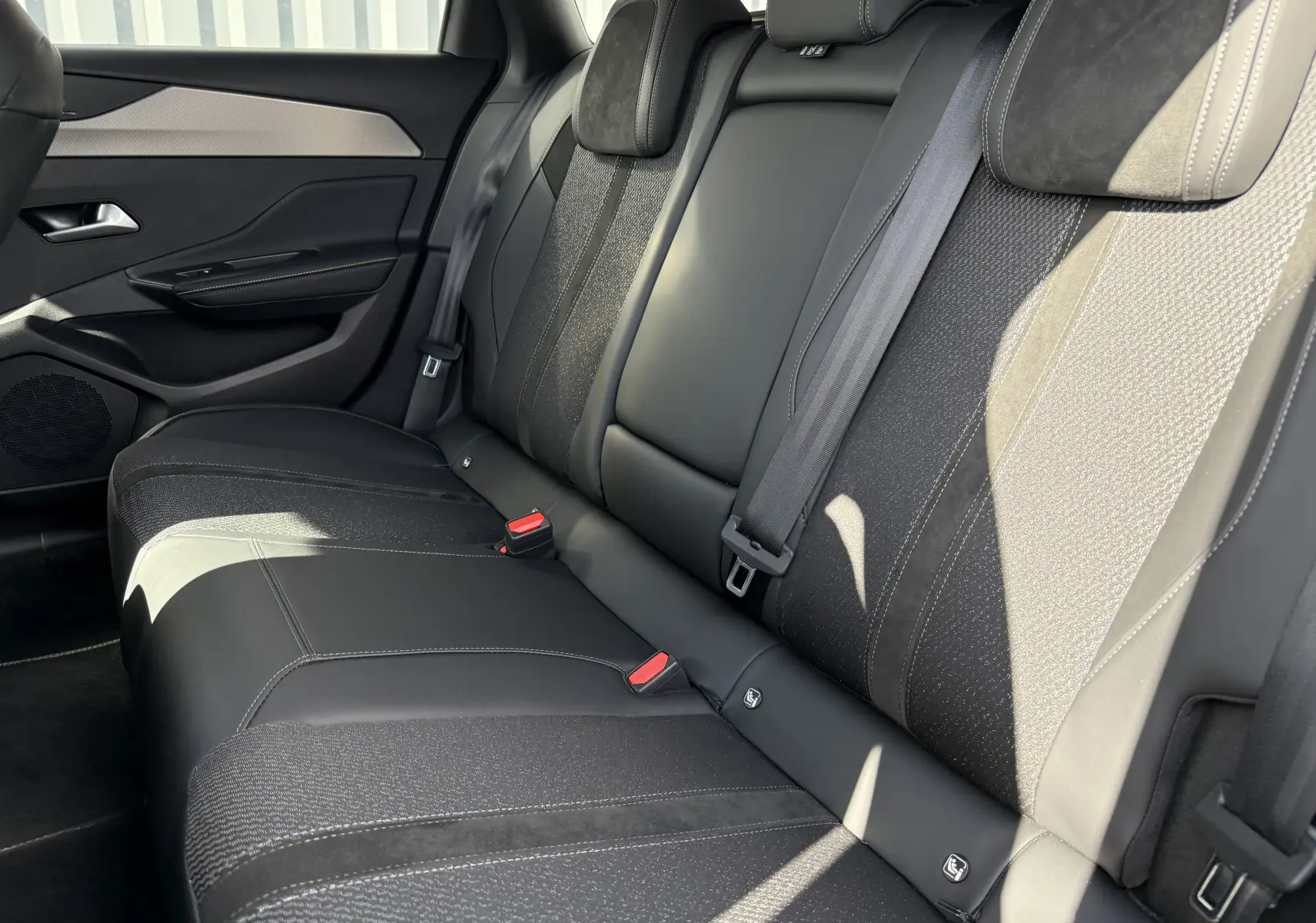 Vue latérale droite des sièges arrière en cuir et tissu noir de la Peugeot 308 SW BlueHDi 130 EAT8 GT 2024.