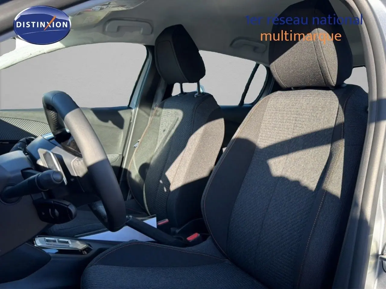 Vue intérieure côté conducteur du Peugeot 208 gris avec sièges tissu gris et volant multifonction.