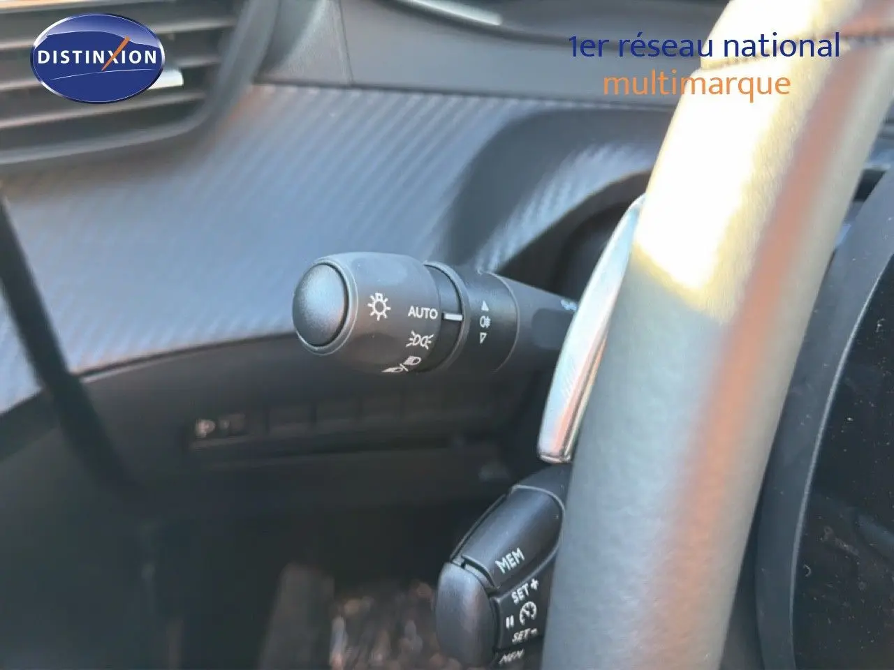 Gros plan sur la commande des phares et régulateur de vitesse derrière le volant d'une Peugeot 208 gris Artense 2025.