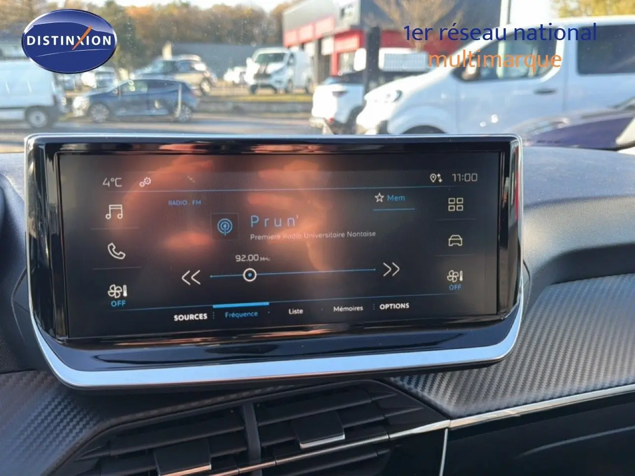 Écran tactile central allumé affichant la radio dans l'habitacle d'une Peugeot 208 gris Artense 2025.